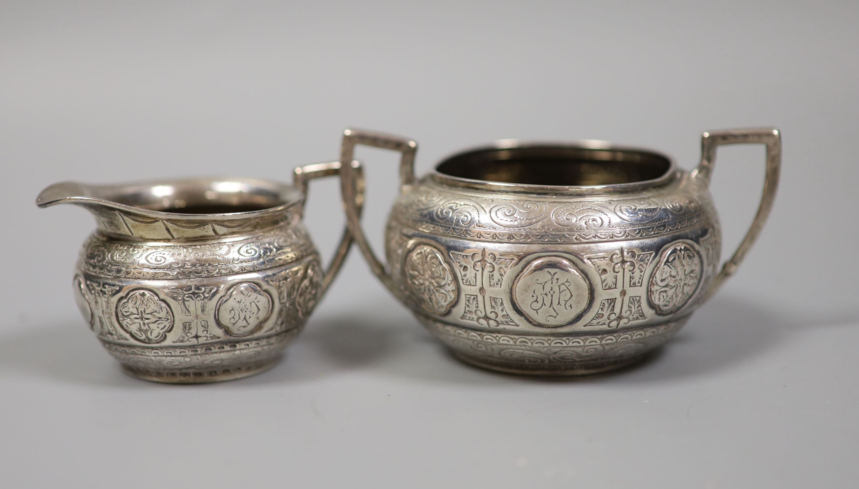 A Victorian engraved silver bachelors cream jug and sugar bowl and pair of matching sugar tongs, Fenton Brothers, Sheffield, 1876, 7.5oz.